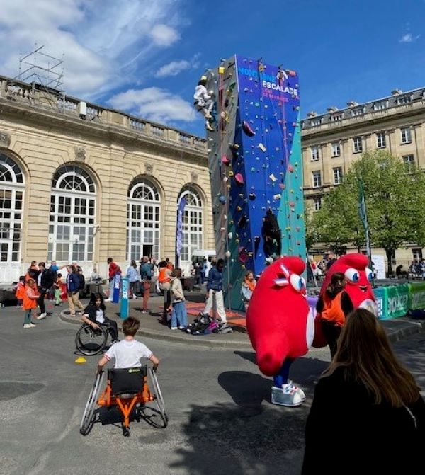 Des enfants sur un mur d'escalade et les mascottes de l'événement France en forme
